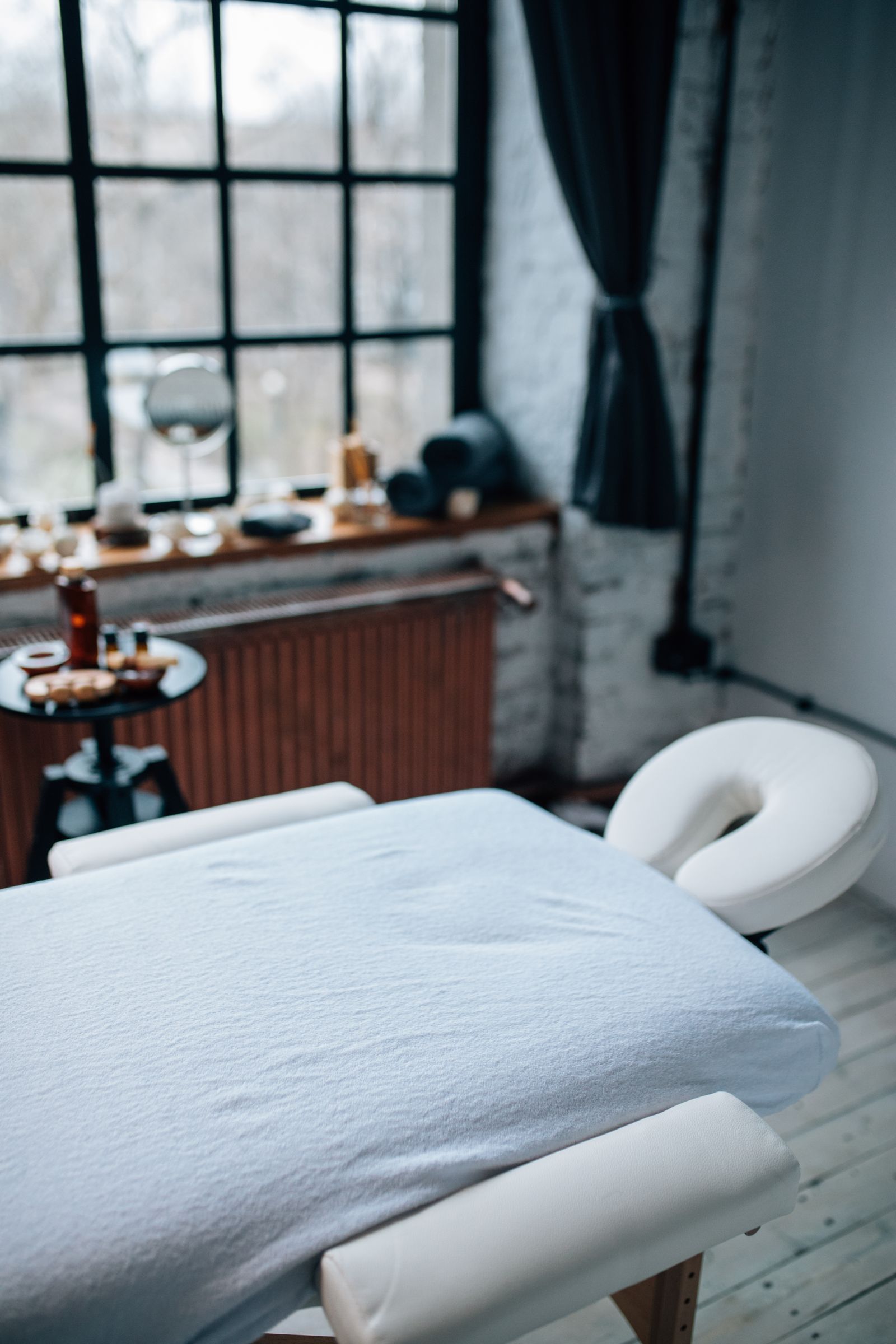 Calm treatment room set up for a remedial massage session, with a covered massage table and treatment tools nearby